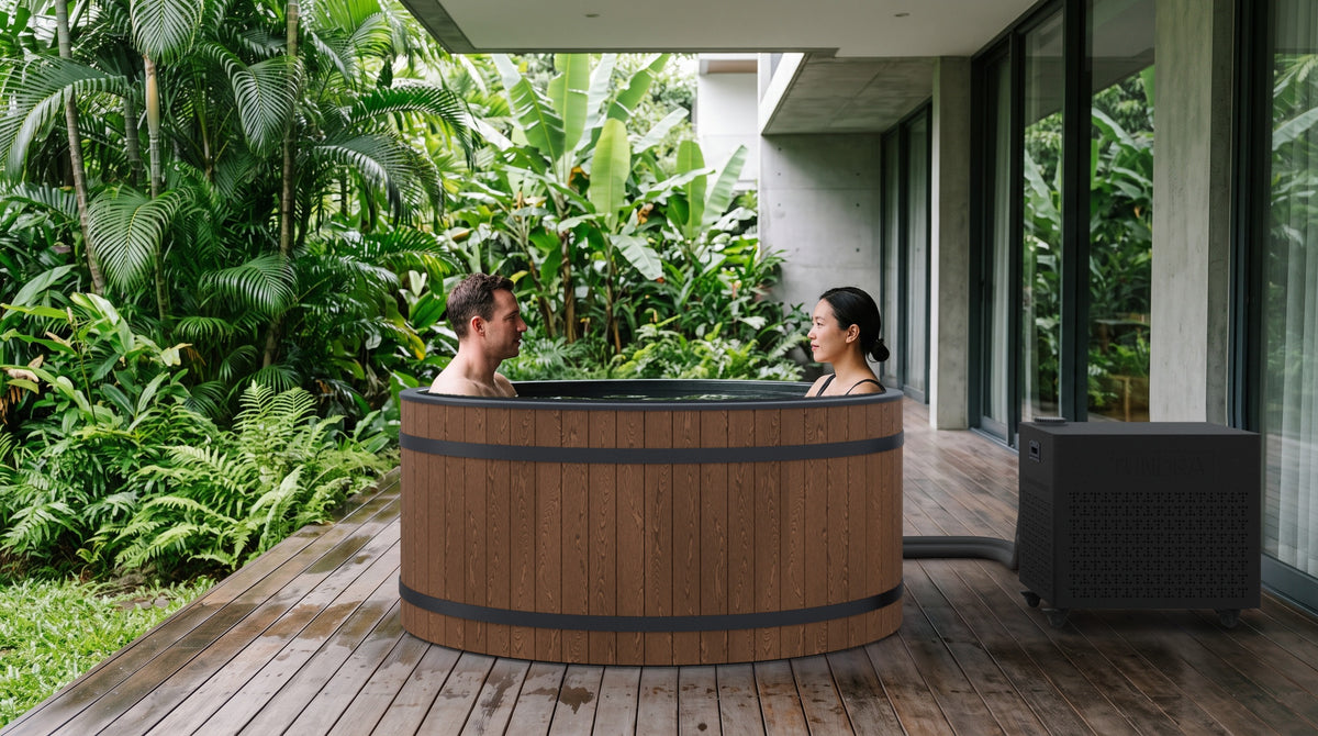 Two people sitting facing each other in the Inari on a garden deck, the Borealis chiller connected beside the tub